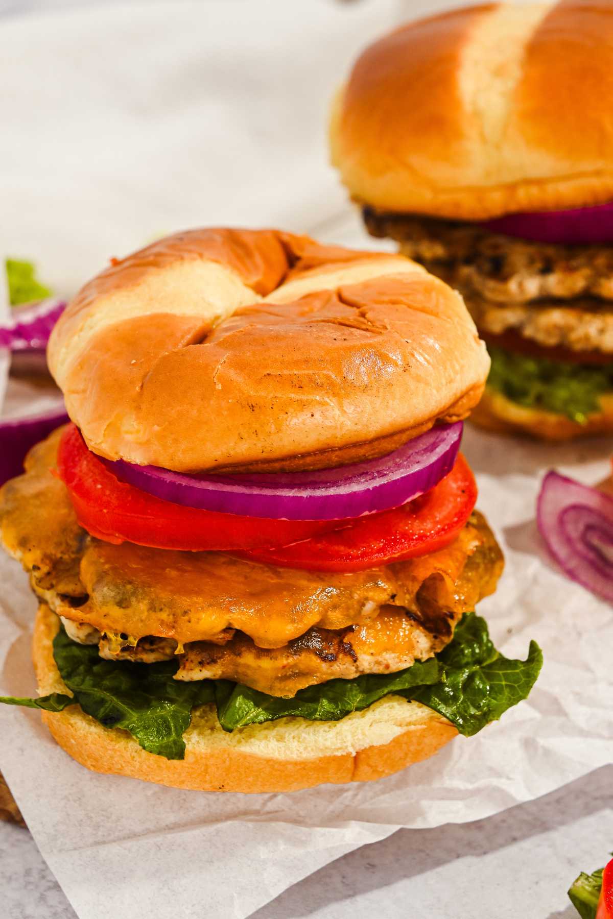 two juicy turkey smash burgers on buns on top of parchment paper.