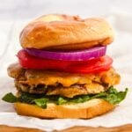 stacked turkey smash burger with cheddar cheese, lettuce, tomato, and onion on a bun.