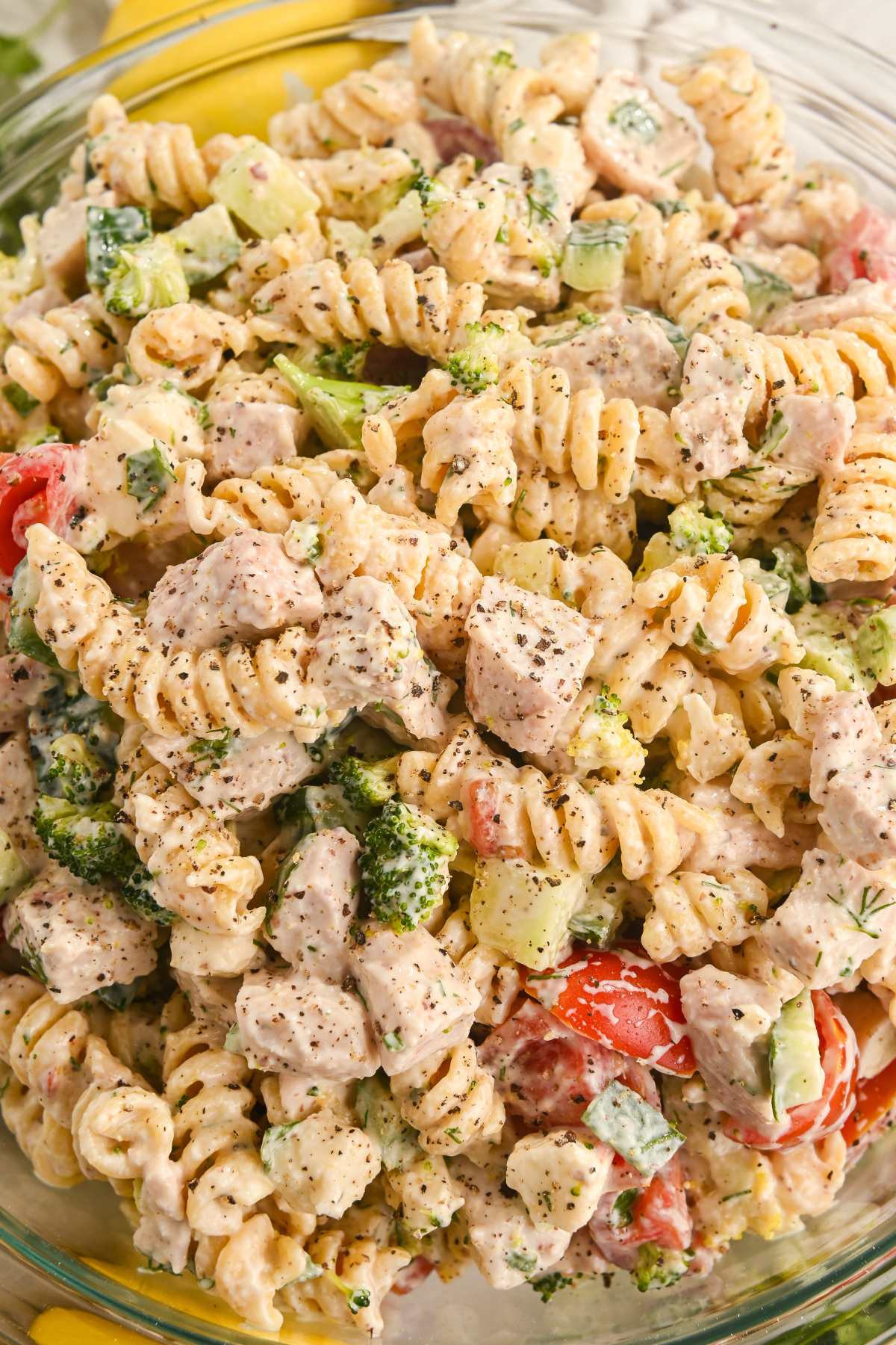 close up of creamy protein pasta salad with vegetables and chicken and topped with black pepper.
