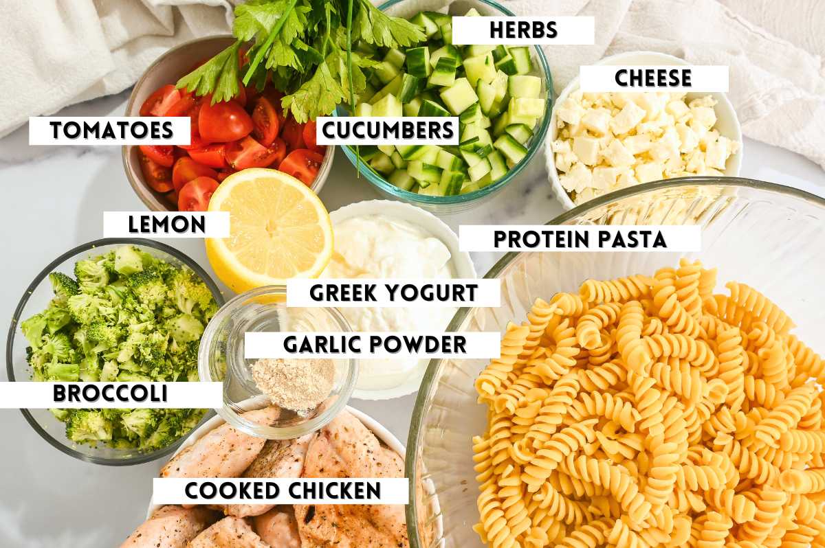 labeled ingredients for making creamy pasta salad with chicken in a flat lay photo.