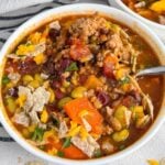 high protein chili in a white bowl with beans, veggies, and ground turkey showing.
