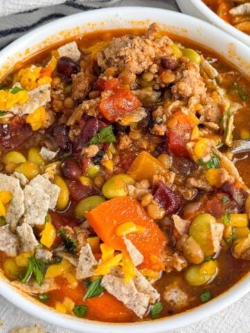 high protein chili in a white bowl with beans, veggies, and ground turkey showing.