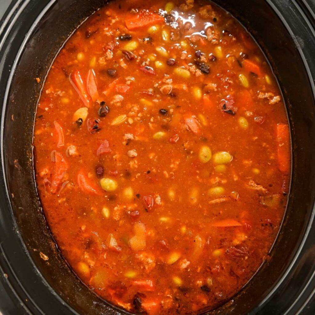 high protein chili cooking in a black crock pot.