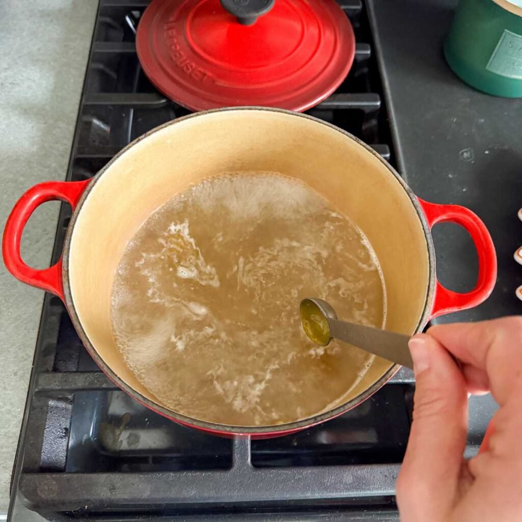 boiling water on the stove in a red pan.