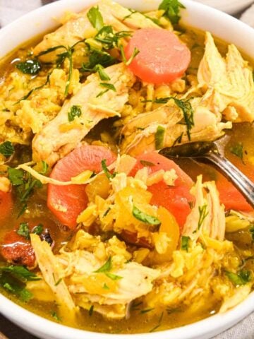 close up of chicken and rice soup in a white bowl.