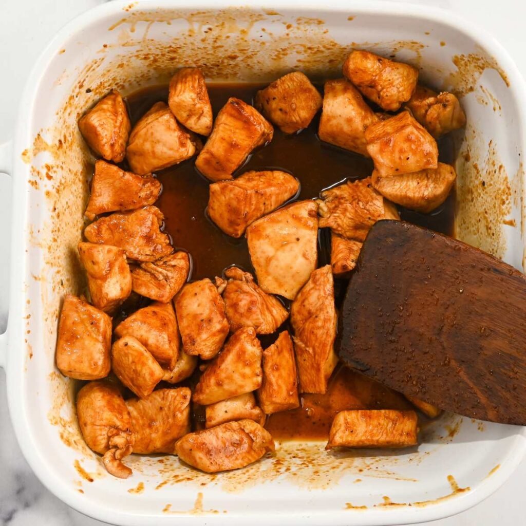 cooked hot honey chicken bites in a white dish with glaze.