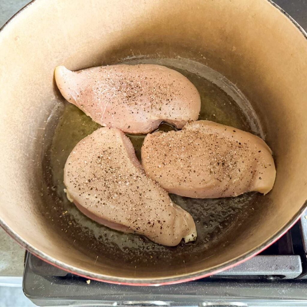 raw chicken breast with salt and pepper in a dutch oven.