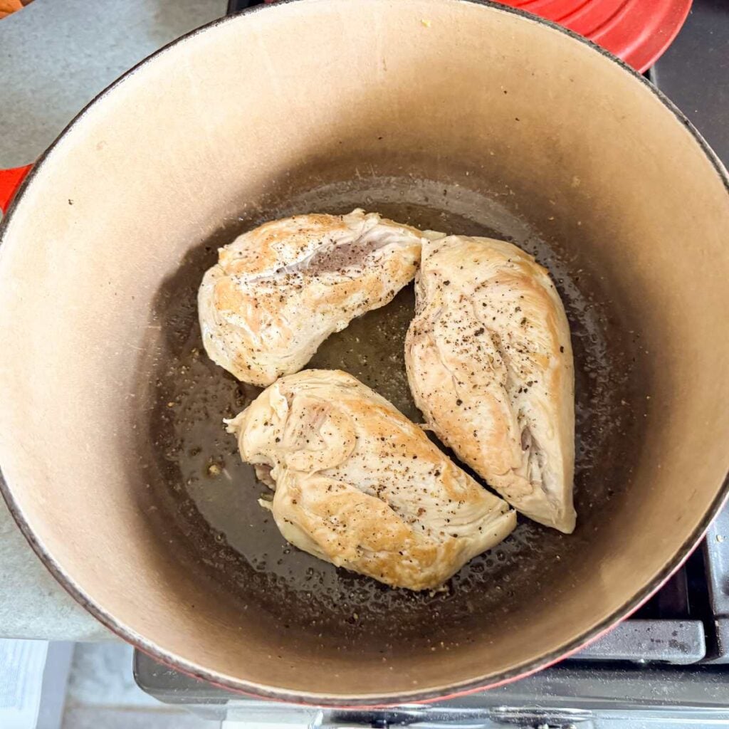 seared chicken breast seasoned with salt and pepper in a Dutch oven.