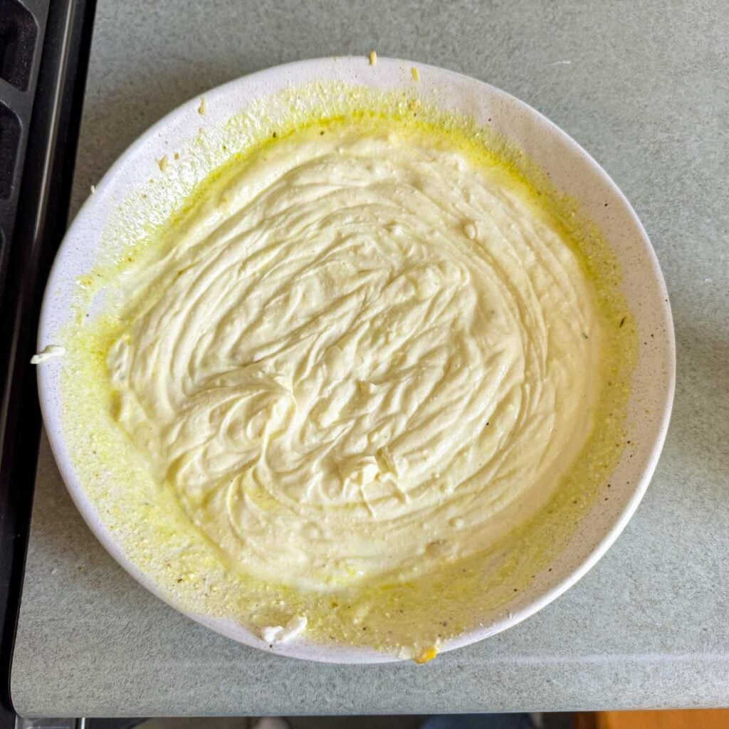 Greek yogurt and chicken broth in a white bowl.