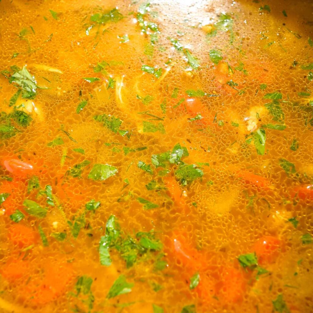 close up of chicken and brown rice soup topped with fresh herbs.