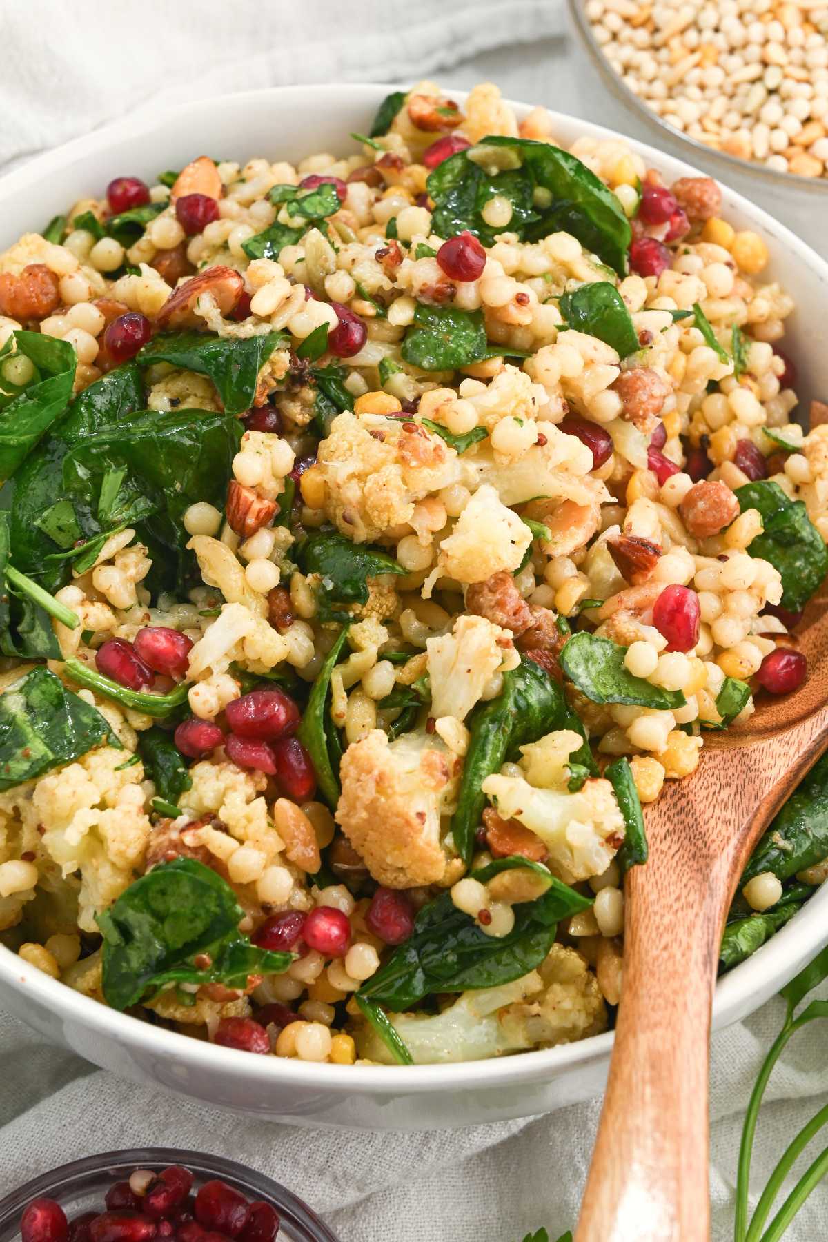 Bowl of winter cauliflower salad with a wooden spoon.