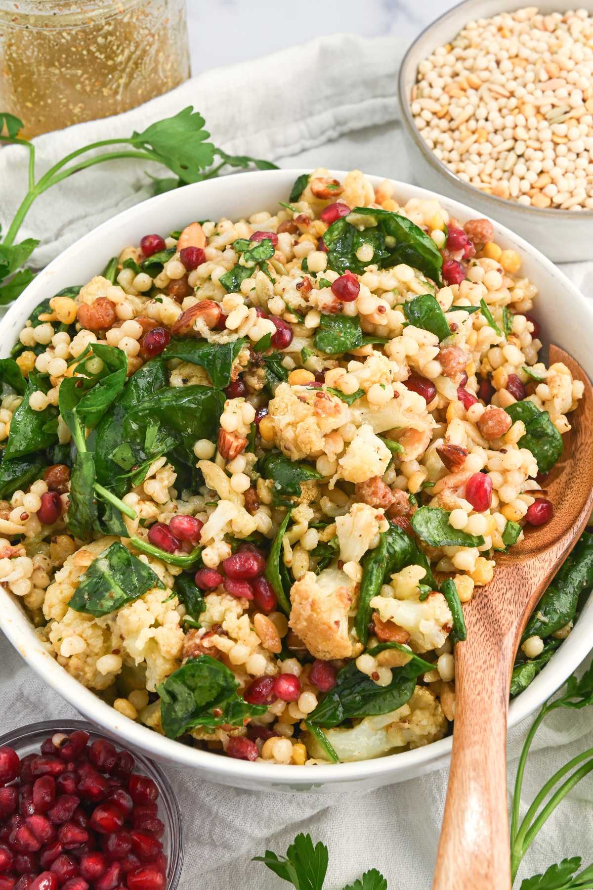 bowl of winter cauliflower salad on a white background with ingredients around.