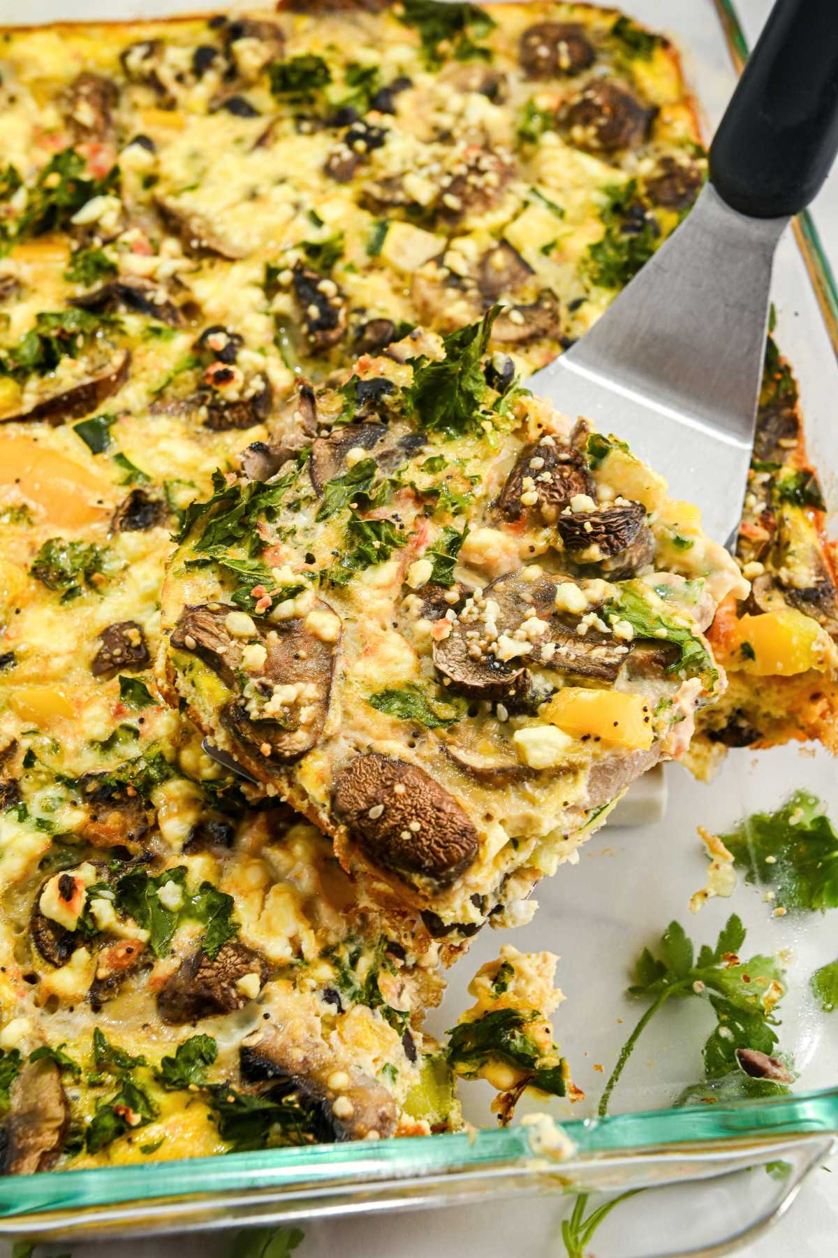 close up of veggie egg breakfast casserole with a spatula holding one piece.