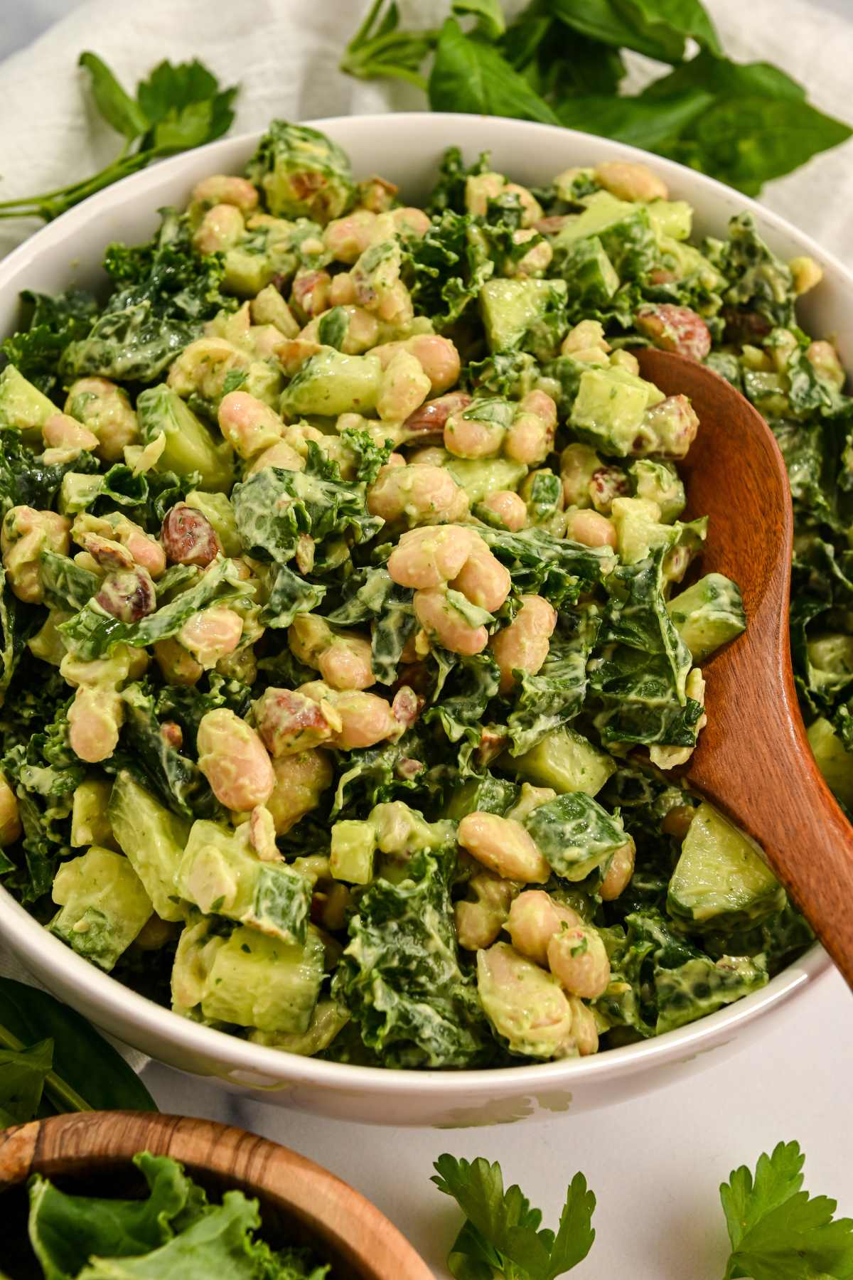 green power salad in a white bowl with a wooden spoon.