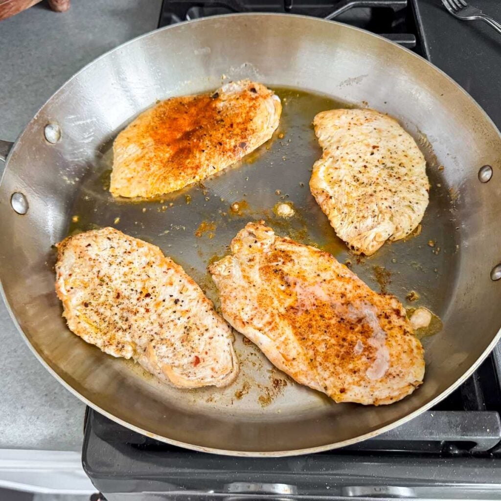 cooking thin chicken breast in a stainless steel skillet.
