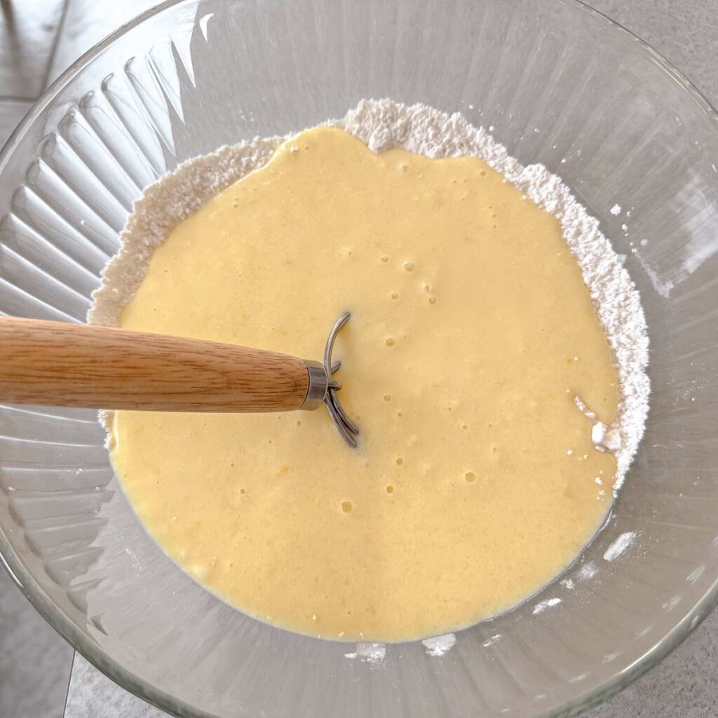 combined dry and wet ingredients in a glass bowl with a dough whisk.