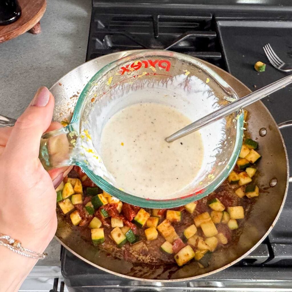 making greek yogurt lemon garlic sauce in a glass cup.