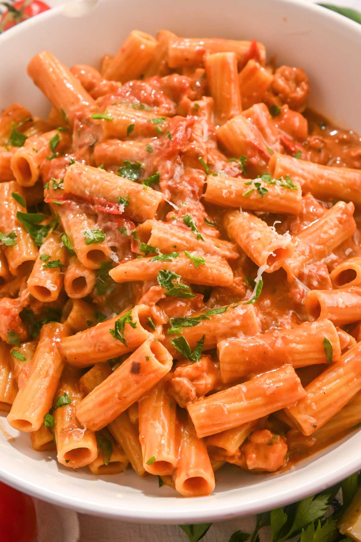 lobster bisque pasta in a white bowl topped with fresh basil and parmesan cheese.