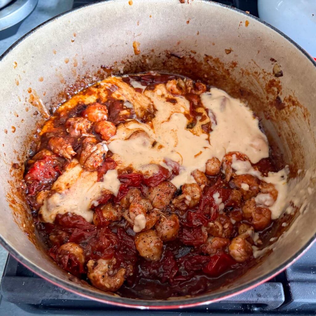 lobster tails, lobster bisque, and tomatoes in a pot on the stove.