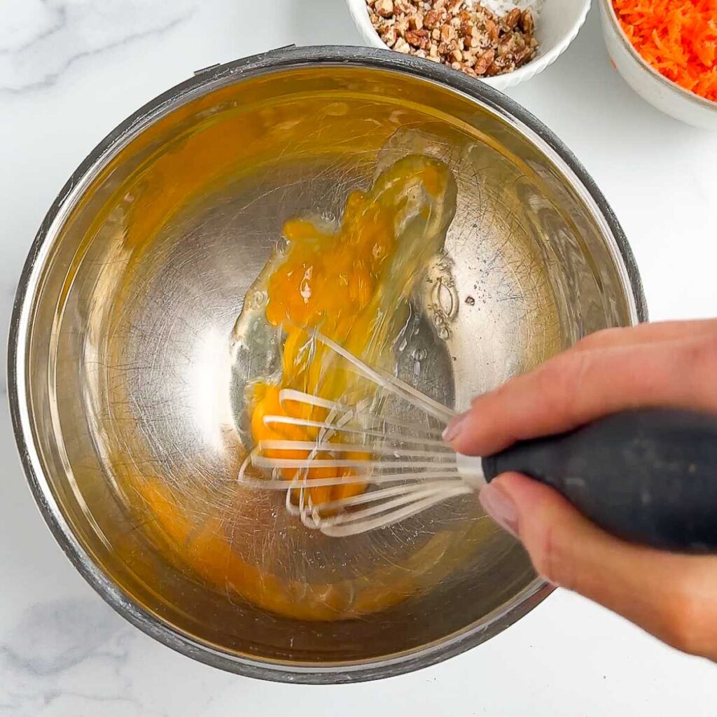 whisking eggs in a silver metal bowl.